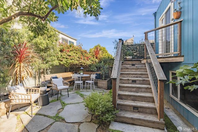 a view of a patio with couches table and chairs with wooden floor and fence