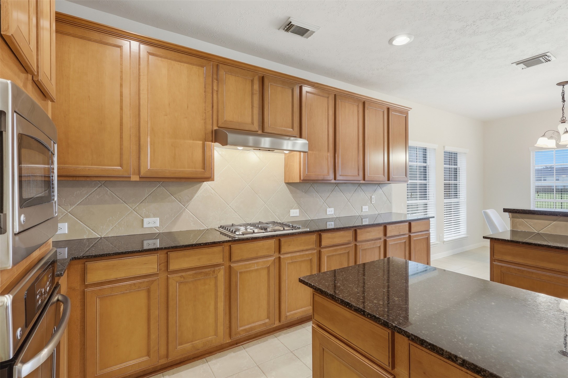 13806 Cove Landing Lane Rosharon, TX 77583 - Photo 13 of 44 Extensive cabinetry, granite counters, a tile backsplash, and built-in cooking features provide excellent kitchen workspace and storage.