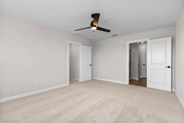a view of an empty room and chandelier fan