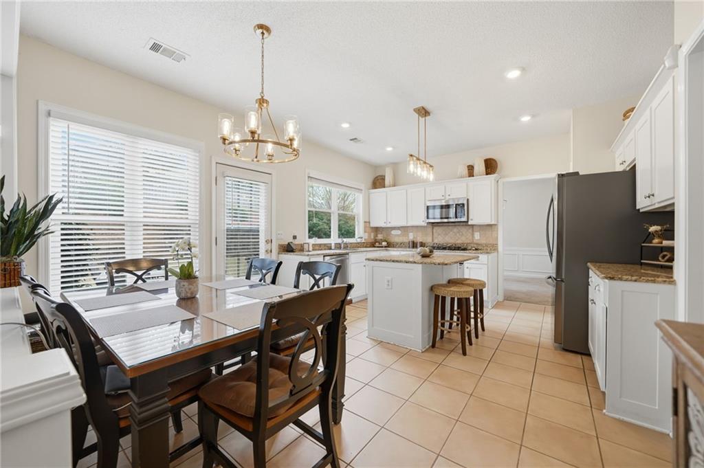 2135 Sugar Maple Lane Northwest Acworth, GA 30101 - Photo 15 of 59 a kitchen with kitchen island a dining table chairs and a refrigerator