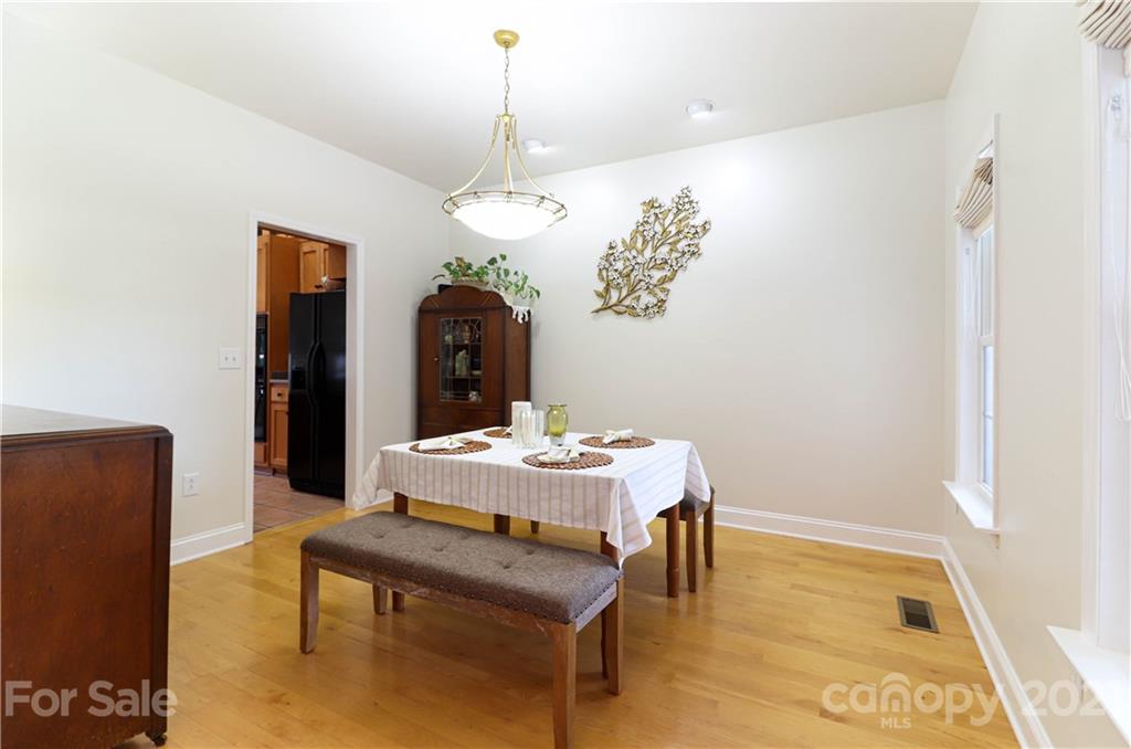 6023 Olive Branch Road Wingate, NC 28174 - Photo 11 of 44 a dining room with wooden floor a chandelier a wooden table and chairs