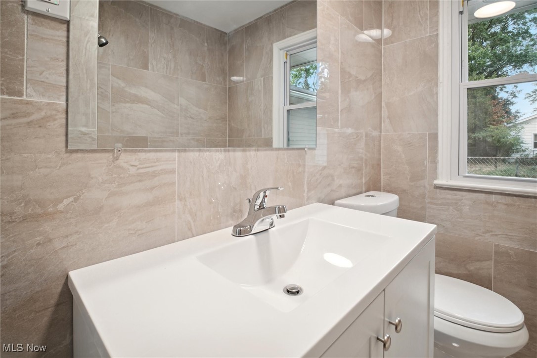 8796 West Ridgewood Drive Cleveland, OH 44130 - Photo 25 of 38 Bathroom featuring vanity, tile walls, and toilet