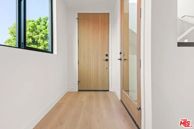 a view of a hallway with wooden floor and a bathroom
