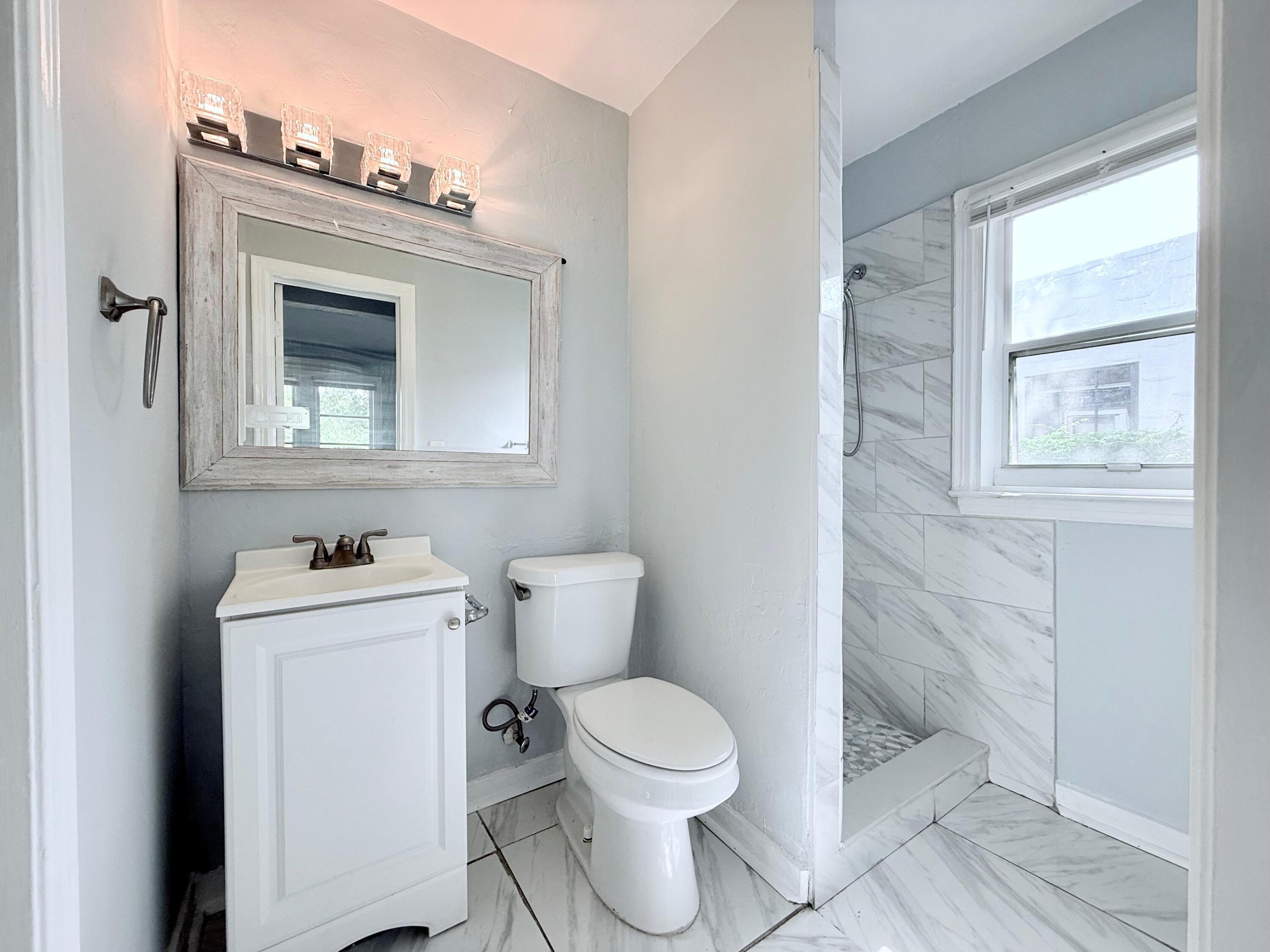 517 Kanuga Drive, Unit 1 West Palm Beach, FL 33401 - Photo 3 of 13 a bathroom with a toilet sink and mirror