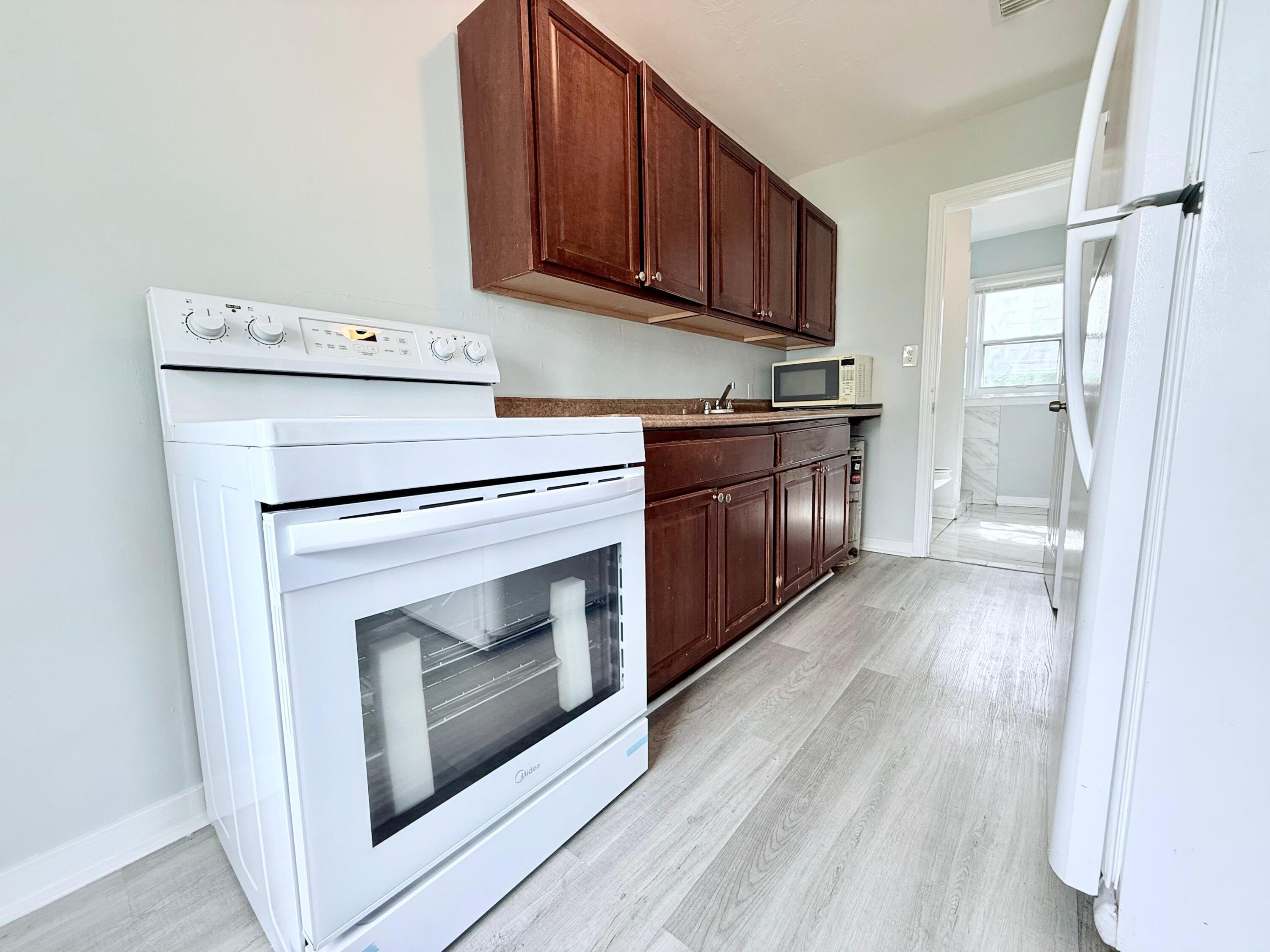 517 Kanuga Drive, Unit 1 West Palm Beach, FL 33401 - Photo 4 of 13 a kitchen with granite countertop wooden cabinets and a stove