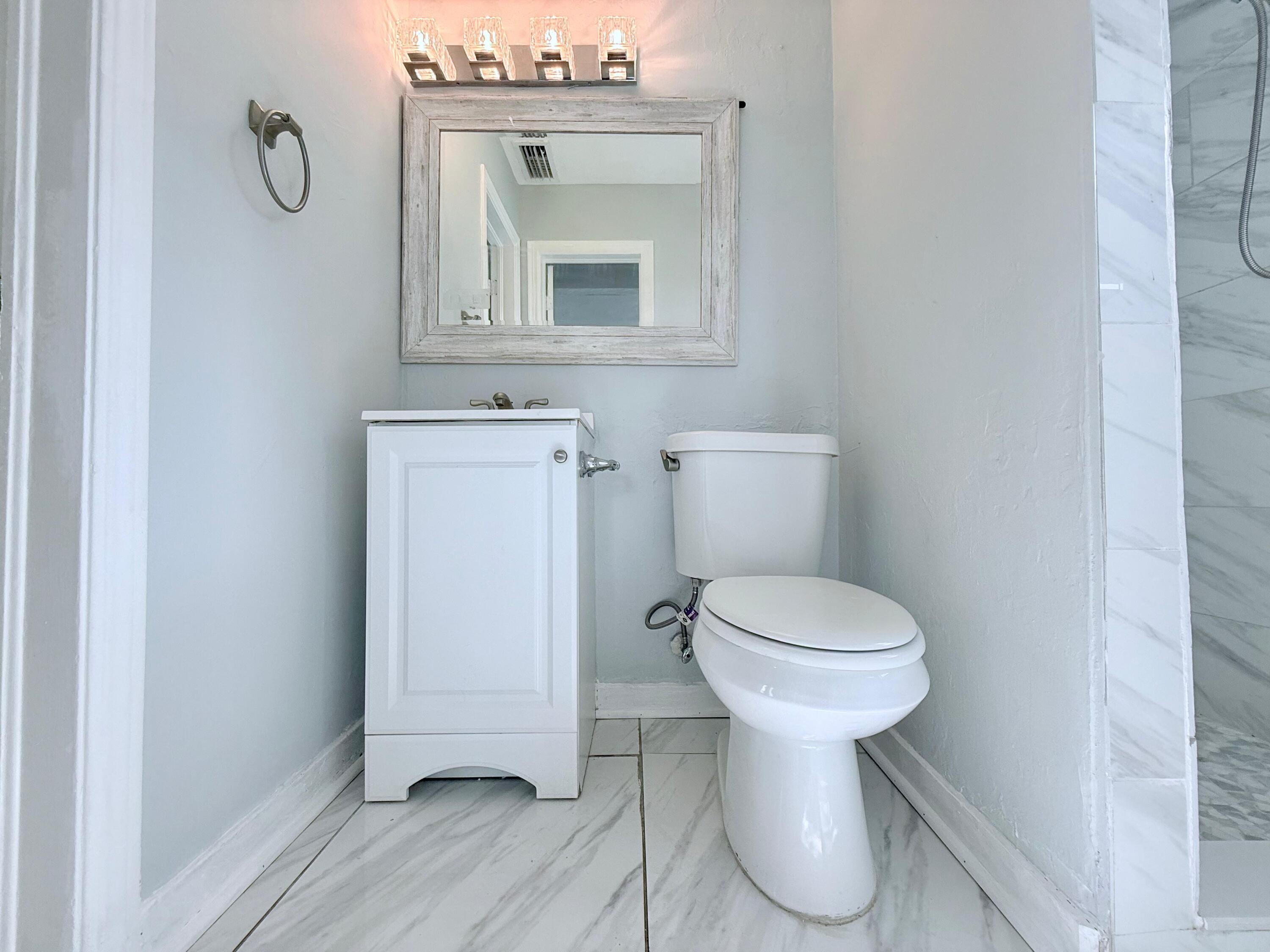 517 Kanuga Drive, Unit 1 West Palm Beach, FL 33401 - Photo 6 of 13 a bathroom with a toilet sink and mirror