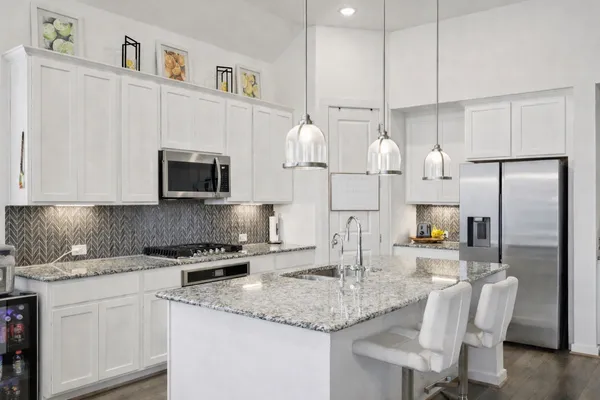 a kitchen with stainless steel appliances granite countertop a sink refrigerator and microwave