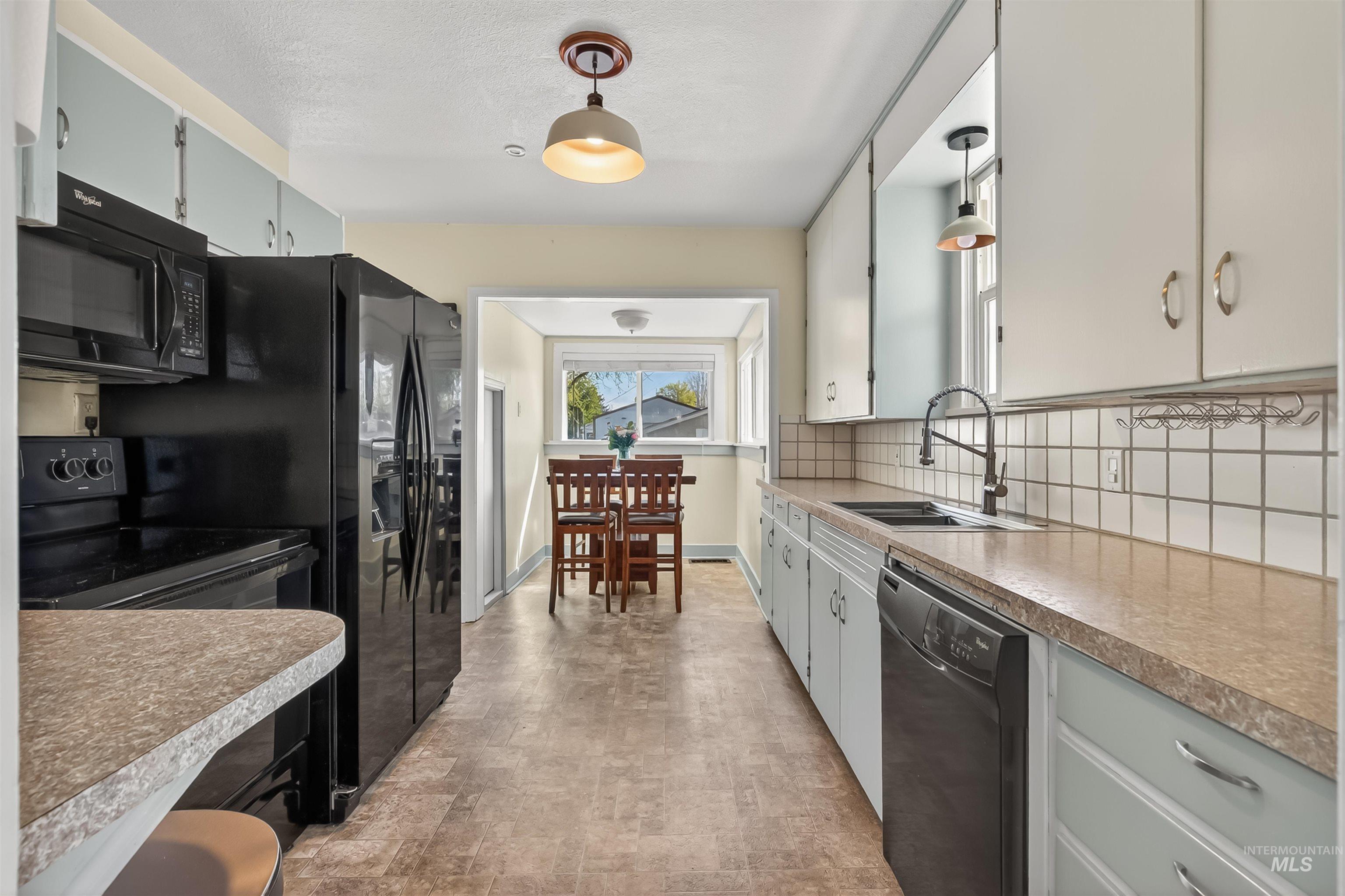 921 3rd Street Clarkston, WA 99403 - Photo 5 of 39 Kitchen featuring black appliances, hanging light fixtures, decorative backsplash, and light countertops
