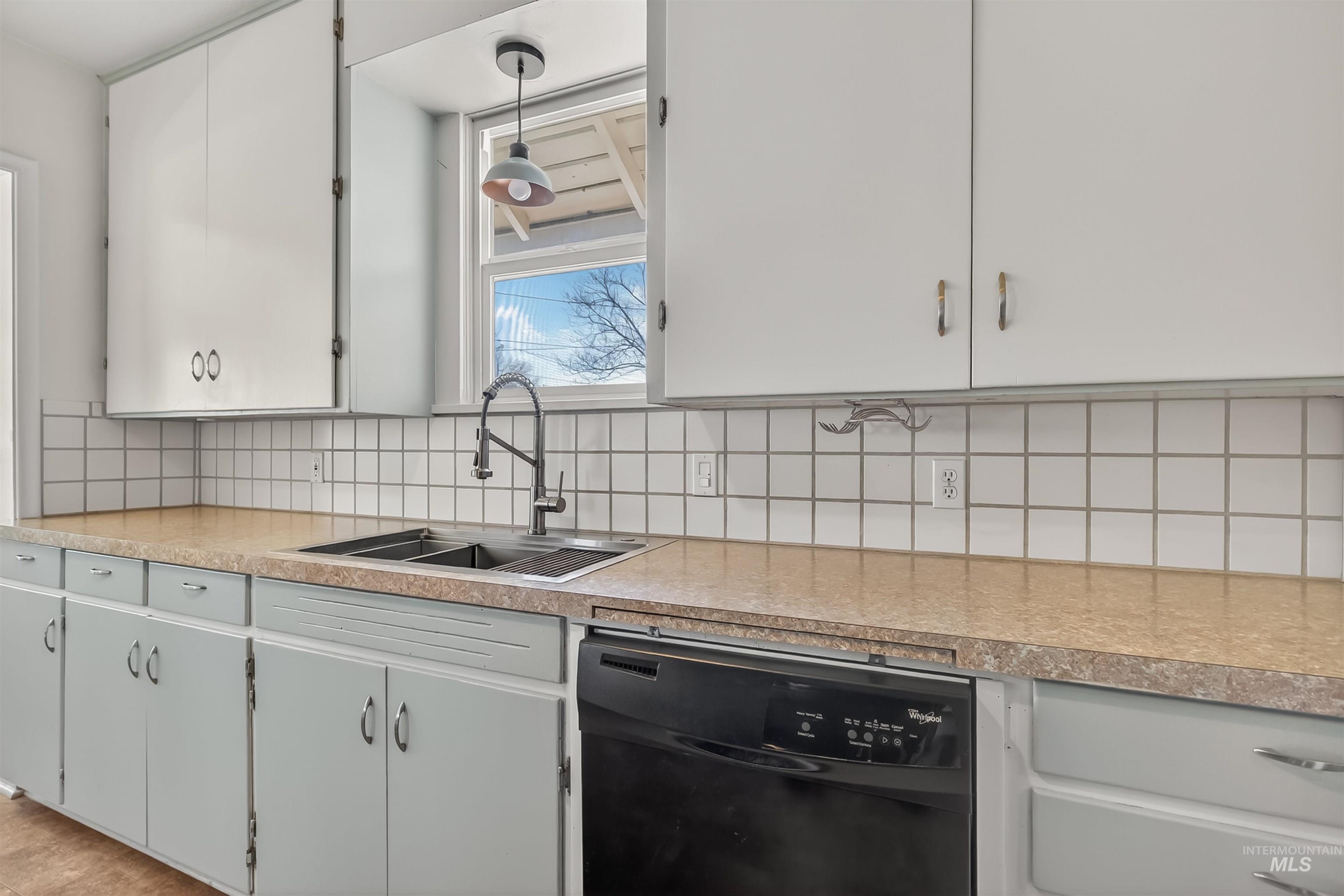 921 3rd Street Clarkston, WA 99403 - Photo 6 of 39 Kitchen with black dishwasher, light countertops, white cabinets, tasteful backsplash, and pendant lighting