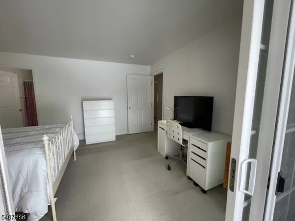 a view of a livingroom with entryway flat screen tv wooden shelves and closet