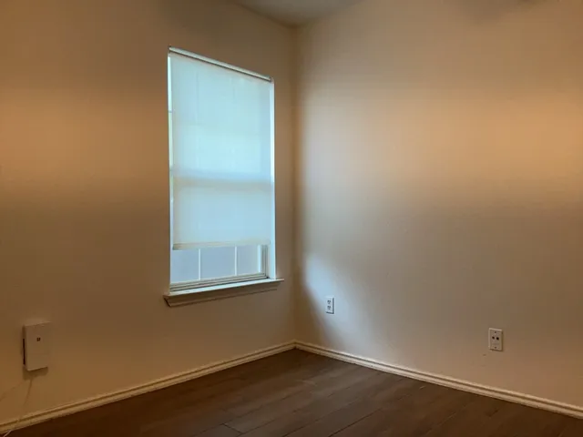 an empty room with a wooden floor and windows
