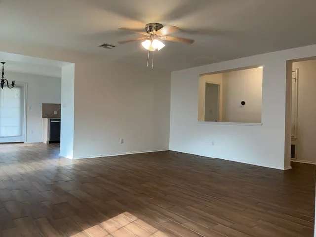 an empty room with wooden floor and a ceiling fan