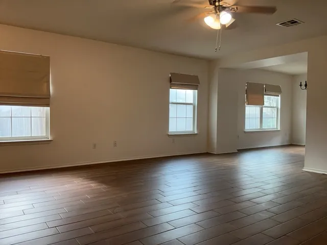 a view of an empty room with wooden floor and a window