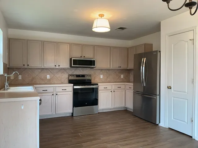 a kitchen with granite countertop a refrigerator stove and microwave