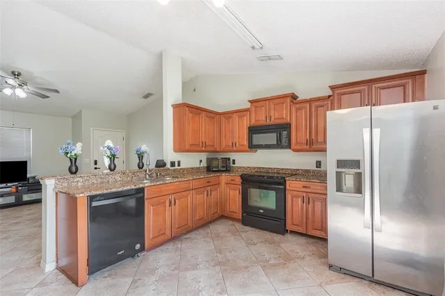 a large kitchen with stainless steel appliances granite countertop a stove refrigerator and a sink