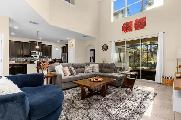 a living room with furniture kitchen view and a large window