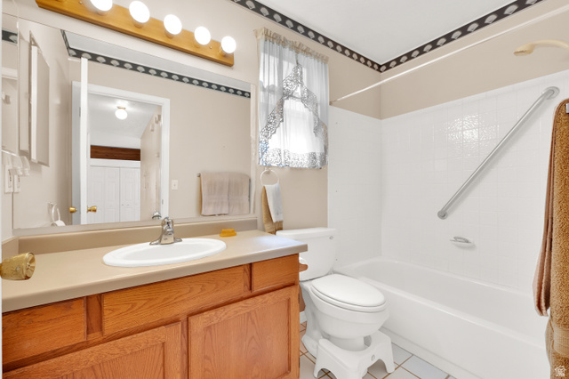 8029 Angel Street Sandy, UT 84070 - Photo 9 of 21 Full bathroom featuring a wood-finish vanity with an integrated sink, a large wall-mounted mirror, a four-bulb vanity light fixture, a toilet, and a bathtub with white tiled walls