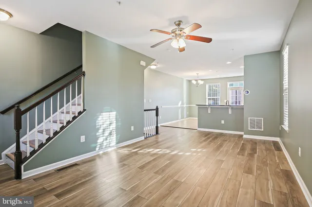 a view of an empty room with wooden floor and a chandelier