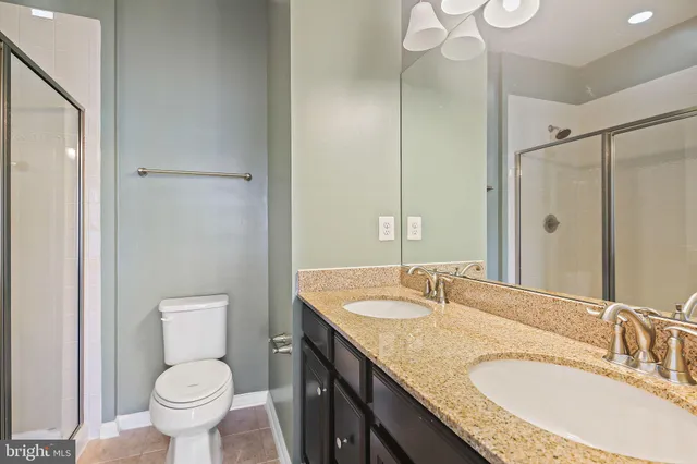 a bathroom with a granite countertop sink a toilet a mirror and shower
