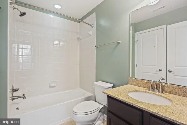 a bathroom with a granite countertop sink toilet mirror and shower