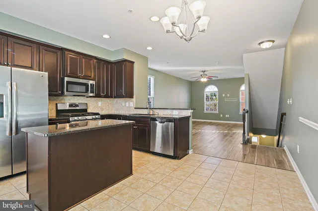 a kitchen with stainless steel appliances granite countertop a sink a stove a refrigerator cabinets and chairs