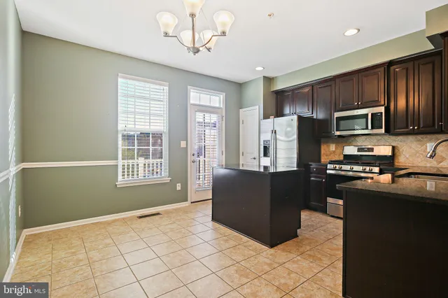 a kitchen with stainless steel appliances granite countertop a refrigerator a stove top oven a sink dishwasher and wooden cabinets