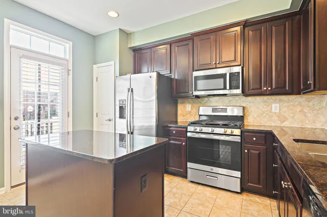 a kitchen with stainless steel appliances granite countertop a stove microwave and refrigerator