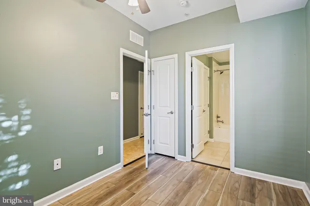 a view of an empty room with closet and wooden floor