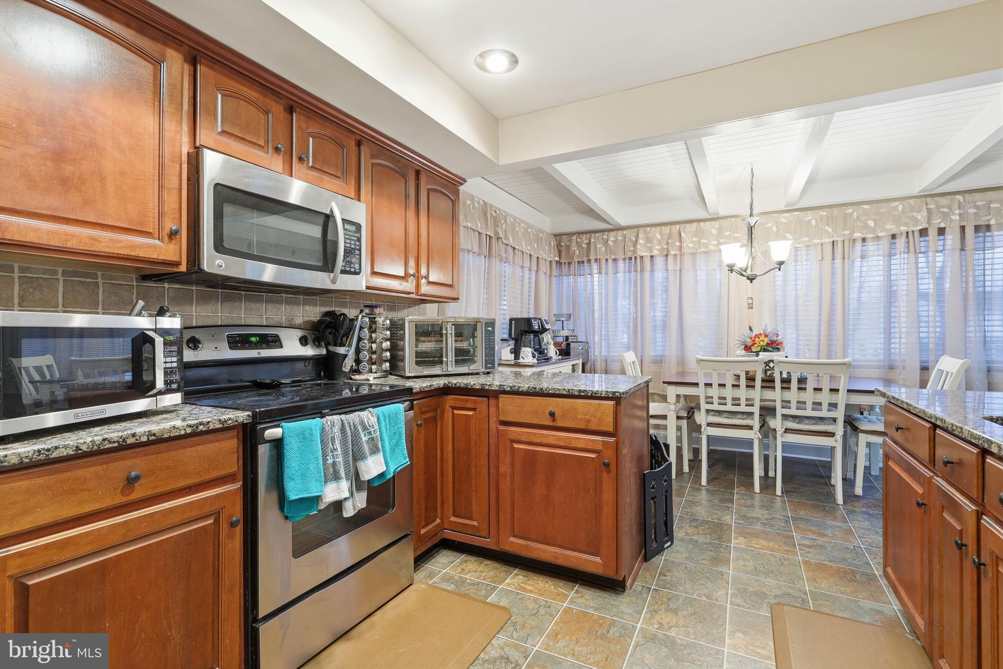 103 Greenvale Road Cherry Hill, NJ 08034 - Photo 13 of 36 a kitchen with stainless steel appliances granite countertop a stove top oven a sink dishwasher a dining table and chairs with wooden floor