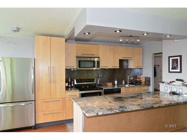 1455 North Sandburg Terrace, Unit 1904 Chicago, IL 60610 - Photo 4 of 7 a kitchen with stainless steel appliances granite countertop a refrigerator a stove a sink dishwasher and a microwave with wooden floor