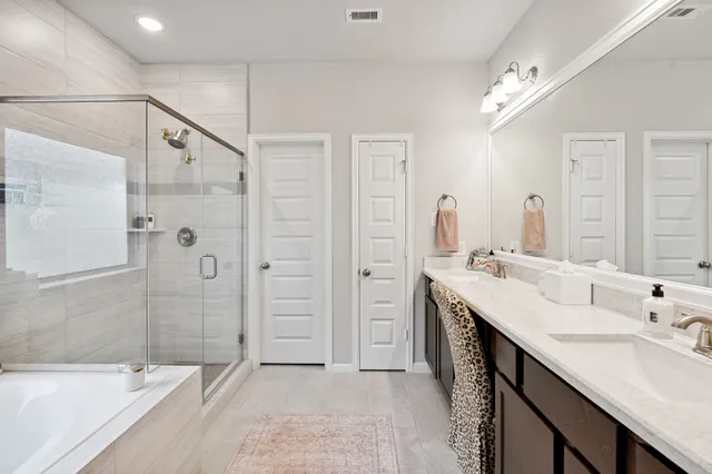 a bathroom with a double vanity sink a large mirror and shower