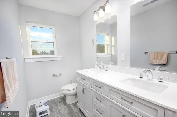 a bathroom with a granite countertop sink toilet and mirror