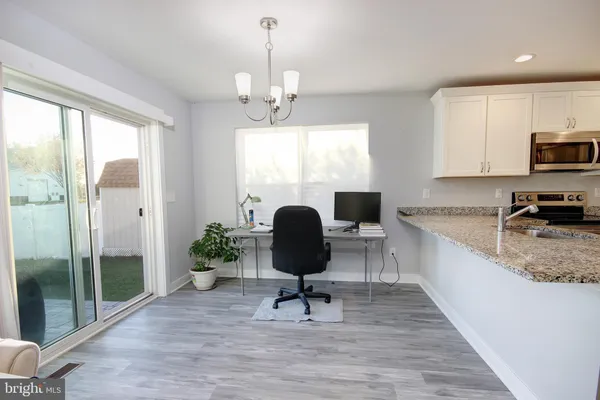 a view of a kitchen with kitchen island granite countertop a window and stainless steel appliances