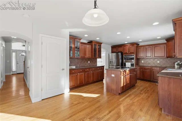 a large kitchen with stainless steel appliances kitchen island granite countertop a large counter top and wooden floors