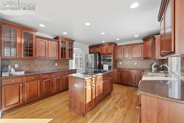 a kitchen with stainless steel appliances granite countertop wooden cabinets a sink dishwasher a stove and a refrigerator