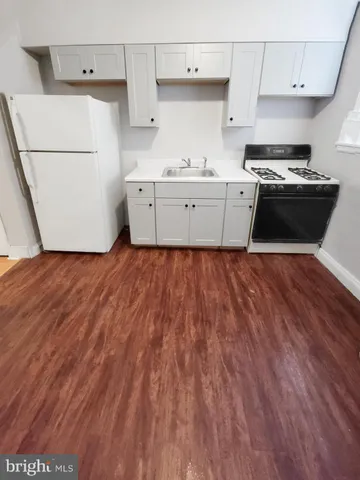 a view of an empty room with wooden floor and stairs