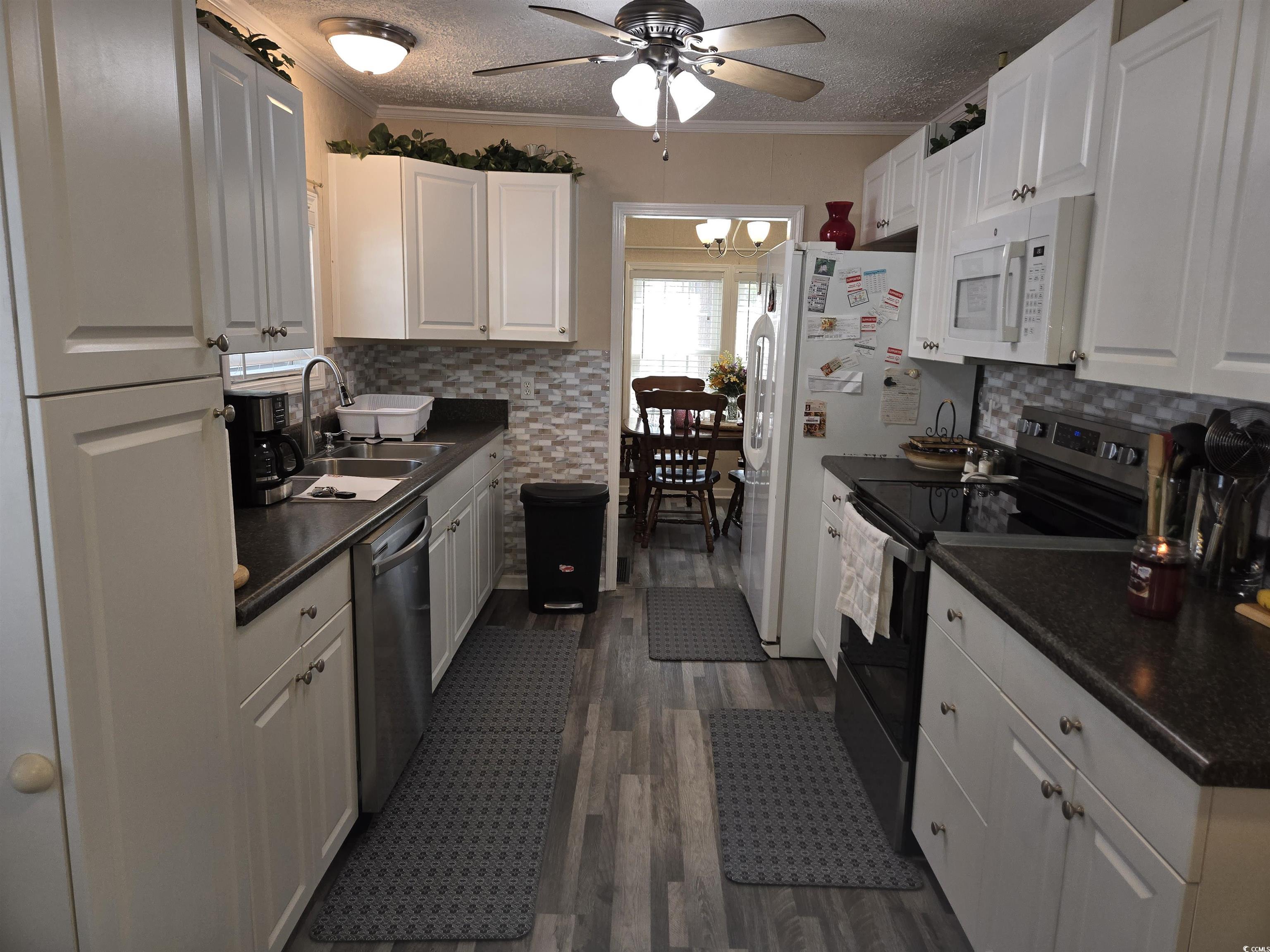 420 Delton Drive Murrells Inlet, SC 29576 - Photo 18 of 36 Kitchen featuring dark countertops, electric range oven, ornamental molding, a textured ceiling, and white cabinetry