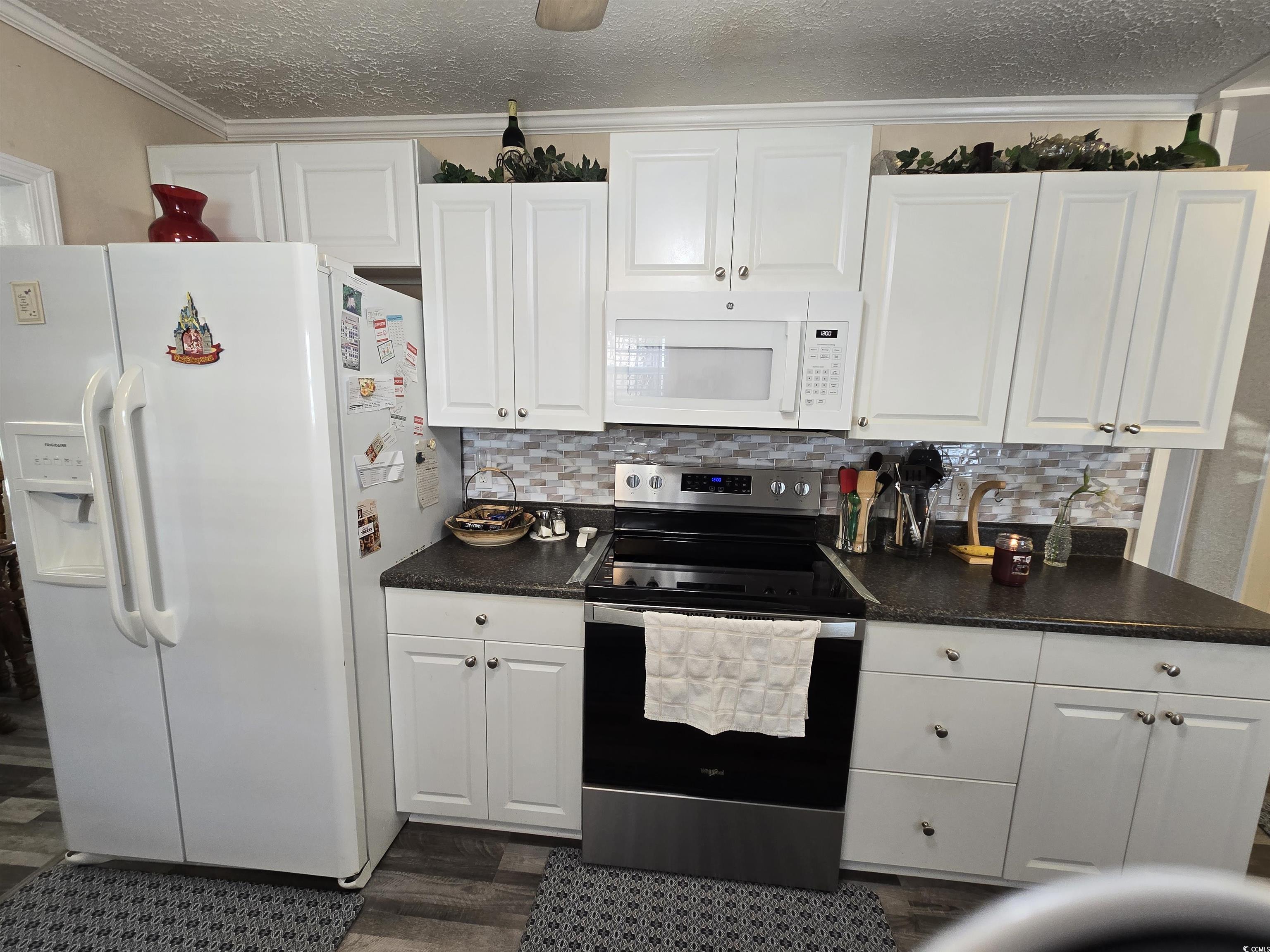 420 Delton Drive Murrells Inlet, SC 29576 - Photo 19 of 36 Kitchen with white appliances, dark countertops, white cabinetry, decorative backsplash, and ornamental molding