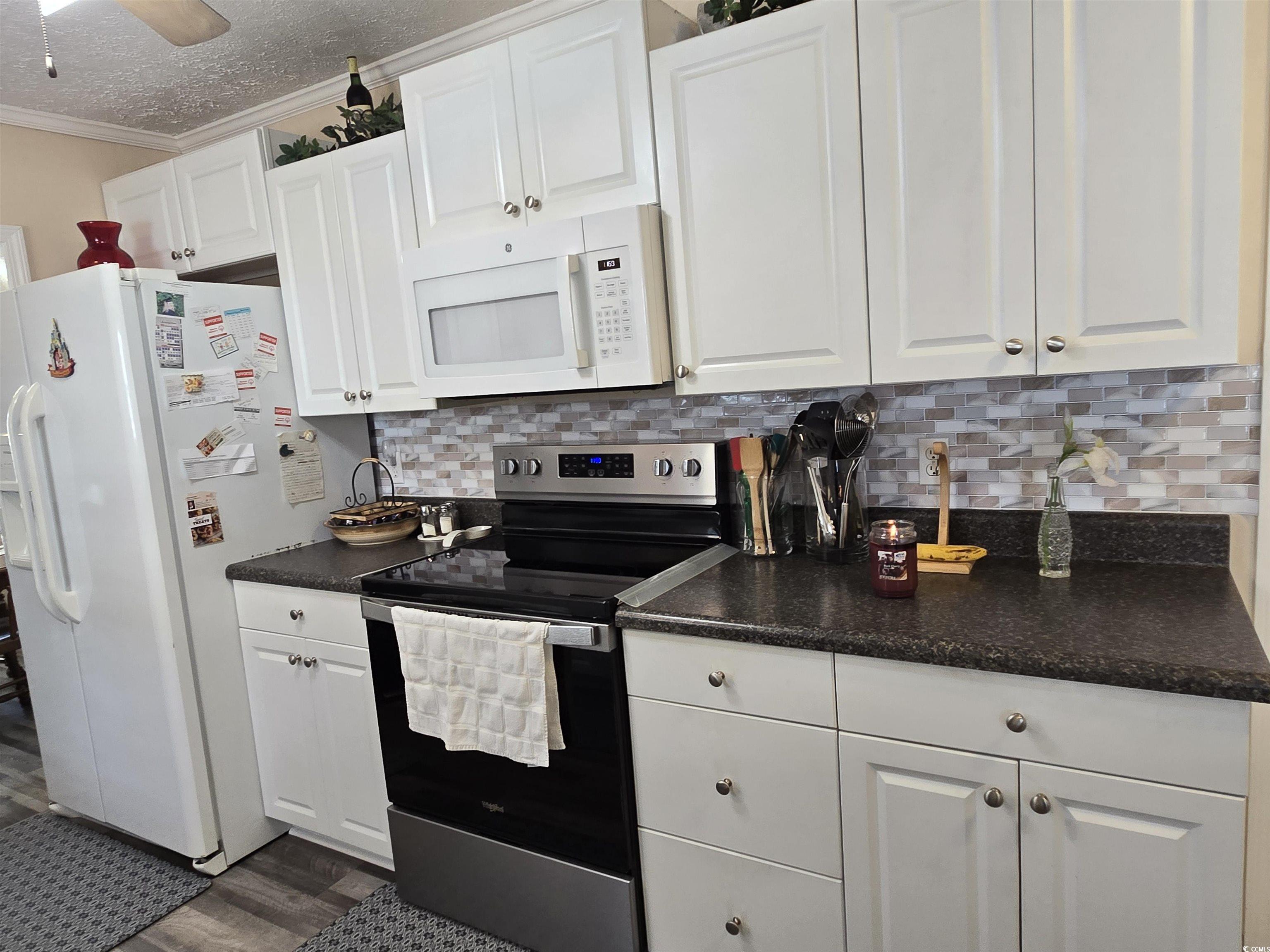 420 Delton Drive Murrells Inlet, SC 29576 - Photo 20 of 36 Kitchen featuring dark countertops, white appliances, decorative backsplash, white cabinets, and a textured ceiling