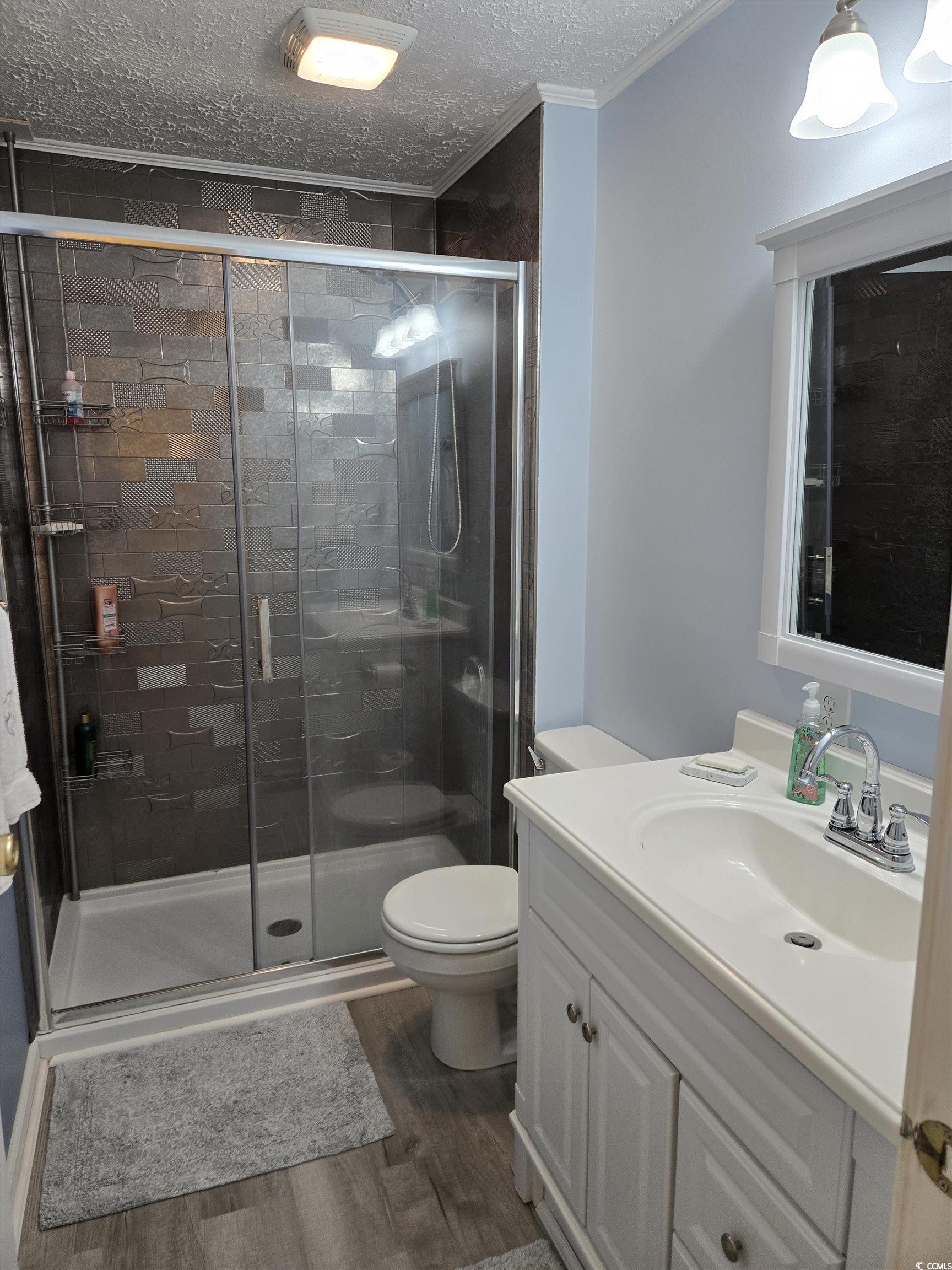 420 Delton Drive Murrells Inlet, SC 29576 - Photo 34 of 36 Bathroom featuring a textured ceiling, vanity, dark wood finished floors, a shower stall, and crown molding