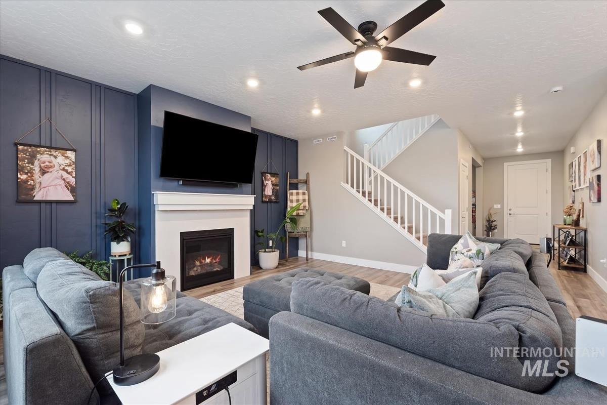 815 Knowledge Street Middleton, ID 83644 - Photo 6 of 49 Inviting living area featuring a fireplace with a white mantel, wood-finish flooring, recessed lighting, and a ceiling fan
