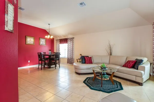 a living room with furniture and a dining table with chairs