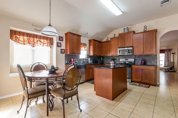 a kitchen with granite countertop a stove a sink a dining table and chairs