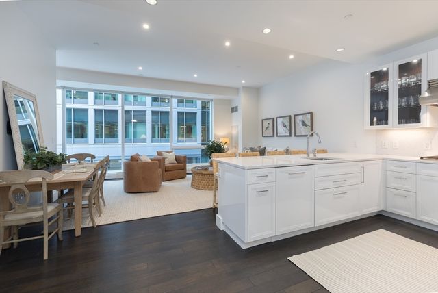 a living room with furniture a flat screen tv kitchen view and a faucet