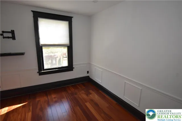a view of an empty room with wooden floor and a window