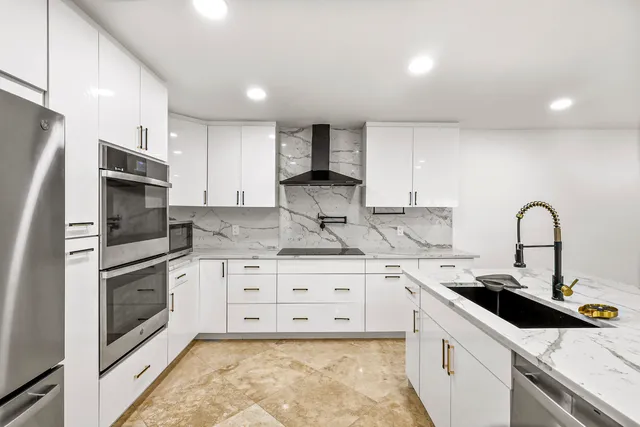 a kitchen with stainless steel appliances granite countertop a sink a stove a refrigerator and cabinets