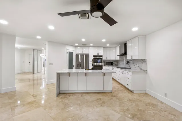 a large white kitchen with kitchen island a sink stainless steel appliances and a counter top