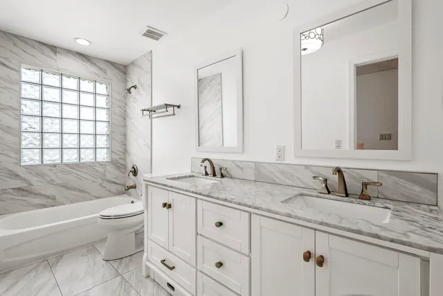 a spacious bathroom with a granite countertop toilet a sink and a bathtub