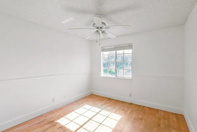 an empty room with a window and a ceiling fan