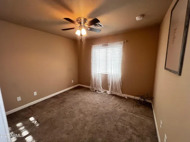 an empty room with chandelier fan and windows